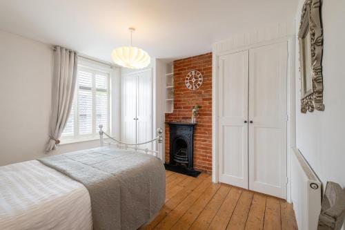 een slaapkamer met een wit bed en een open haard bij Charming Kings road in Bury Saint Edmunds