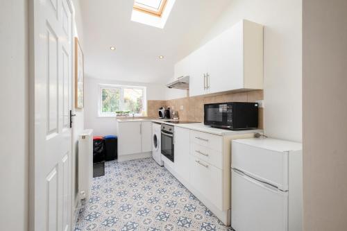 een keuken met witte kasten en een tegelvloer bij Charming Kings road in Bury Saint Edmunds