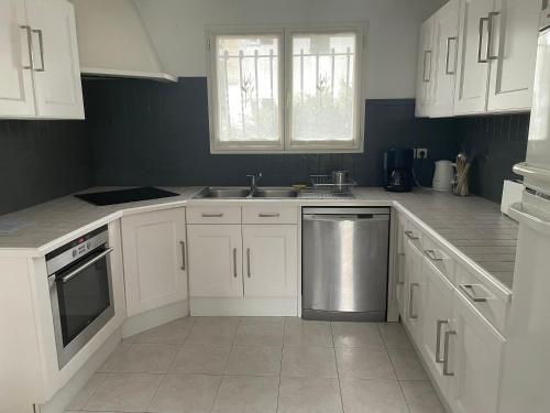 - une cuisine avec des placards blancs et un lave-vaisselle en acier inoxydable dans l'établissement Maison Lore Mendi Elbarron, à Saint-Pée-sur-Nivelle