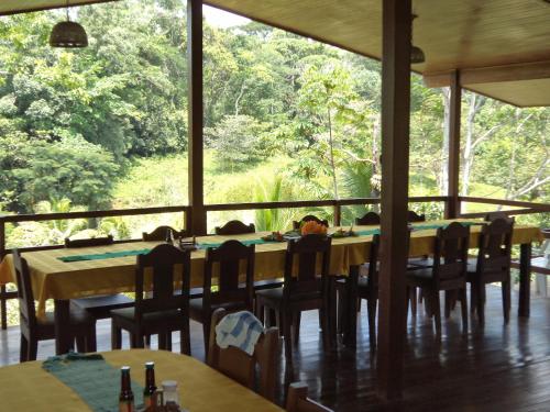 a dining room with tables and chairs and a large window at La Laguna del Lagarto Eco-Lodge in Pital