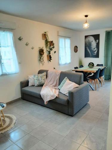 a living room with a couch and a table at Proche aéroport à pied O' jungle in Tillé