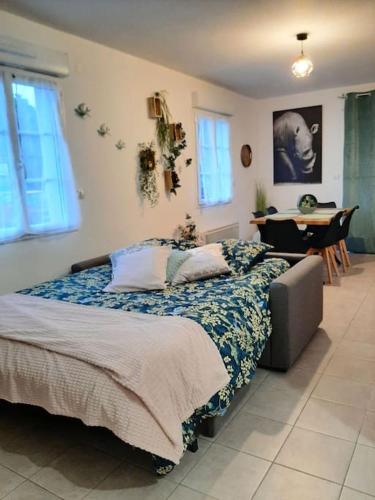 a bedroom with a bed with a blue blanket and a table at Proche aéroport à pied O' jungle in Tillé