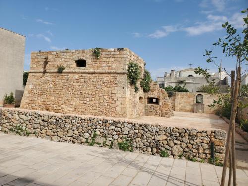 a brick building with a stone wall next to a sidewalk at Casa Cassiano in Patù
