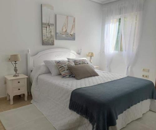 a white bedroom with a bed with a blue blanket at El balcón de Alexia, 5 minutos del aeropuerto in Partida de La Cañada