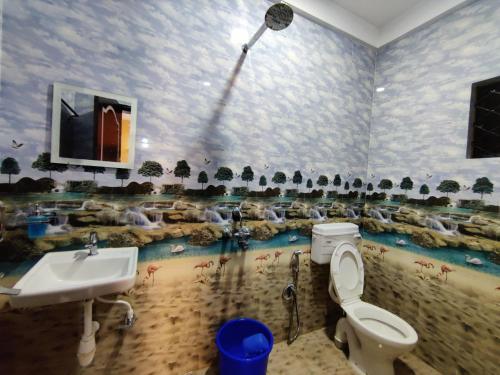 a bathroom with a sink and a toilet and a mural at Sai Guru Guest House in Anjuna