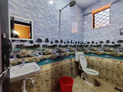 a bathroom with a sink and a toilet and animals on the wall at Sai Guru Guest House in Anjuna