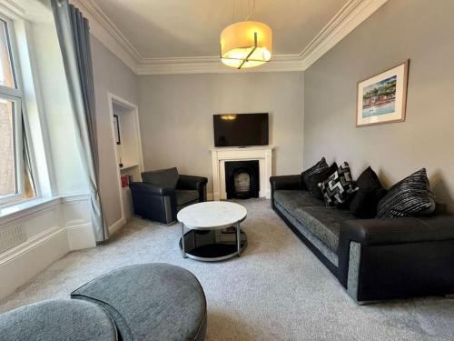 a living room with a couch and a table at Beautiful spacious apartment in town centre in Oban