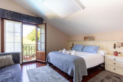 a bedroom with a bed and a couch and a window at Urdaibai Boutique in Altamira