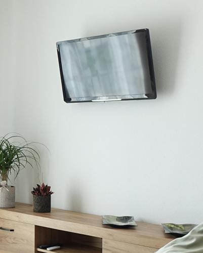 a television hanging on a white wall at ELYs-Home in Isny im Allgäu