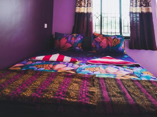 a bed with a colorful blanket and pillows on it at Sai Guru Guest House in Anjuna