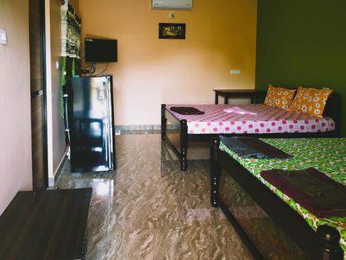 a room with two beds and a couch in it at Sai Guru Guest House in Anjuna