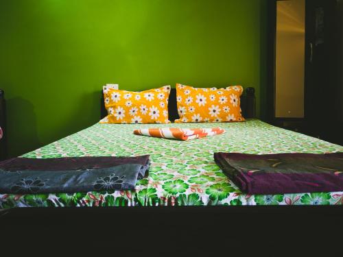 a green bedroom with a bed with colorful pillows at Sai Guru Guest House in Anjuna