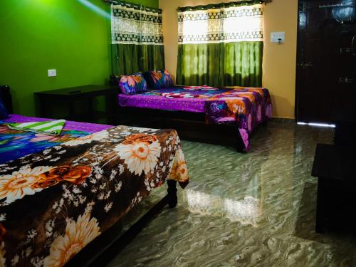 two beds in a room with green and purple at Sai Guru Guest House in Anjuna
