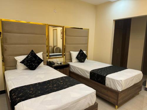 a hotel room with two beds and a mirror at Gold Pine Hotel Lahore in Lahore
