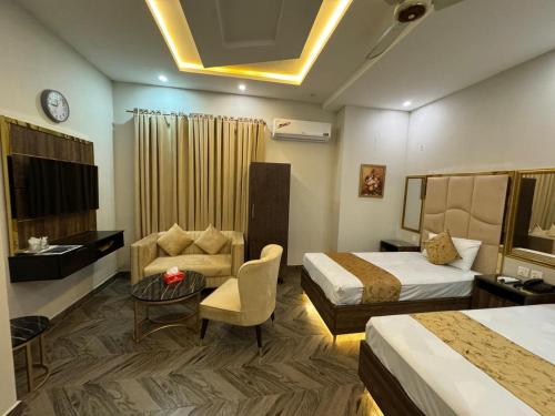 a hotel room with two beds and a couch at Gold Pine Hotel Lahore in Lahore