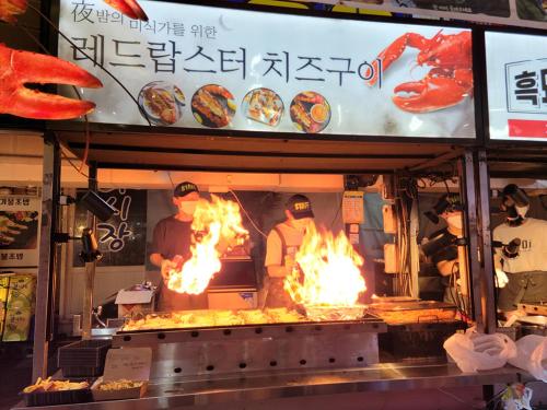 a restaurant with fire inside of a grill with food at Jeju Vision House in Jeju
