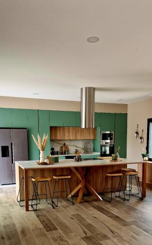 a kitchen with green cabinets and a large island with stools at Casa Julia in Vila Nova de Cerveira
