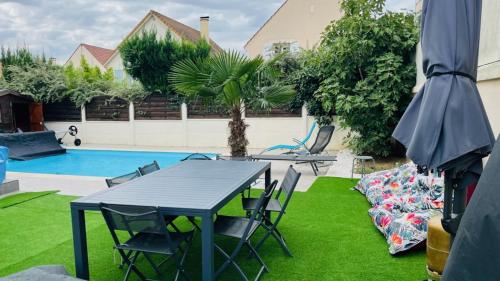 a patio with a table and chairs next to a pool at Charmante maison au Nord de Paris piscine chauffée in Argenteuil