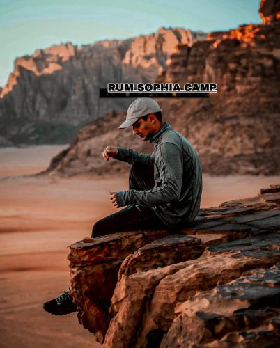 a man sitting on a rock in the desert at Rum Sophia camp in Wadi Rum