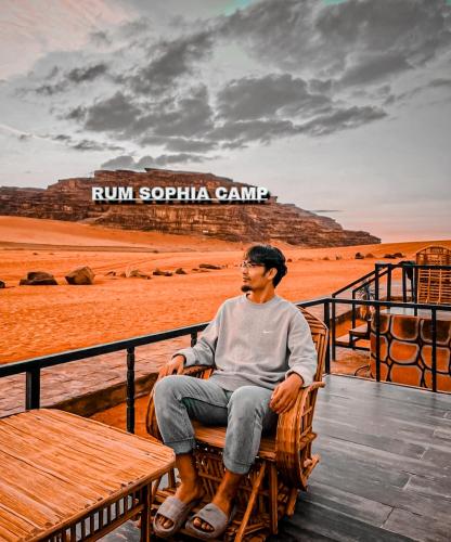 a man sitting on a bench at the beach at Rum Sophia camp in Wadi Rum