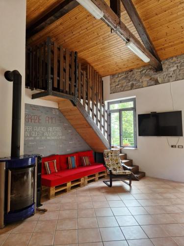 uma sala de estar com um sofá vermelho e uma lareira em La Vrata Gialla em Taipana