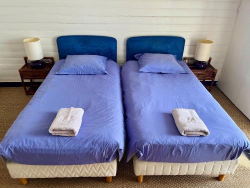 two beds in a room with blue sheets and towels at La Villa Ker Mat in Larmor-Plage