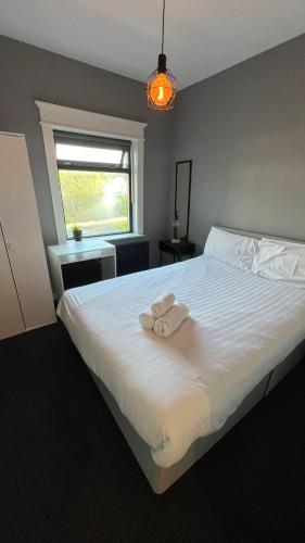 Un dormitorio con una gran cama blanca con una toalla. en Twelve - Boutique Guest House -Galway City Centre -6 Bed En-Suite - Free Parking, en Galway
