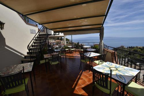 a balcony of a restaurant with tables and chairs at Hotel Condor in Taormina