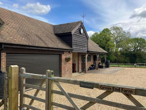 a house with a fence and a gate with a give end farm sign at The Stable, Grove End Farm in Petworth