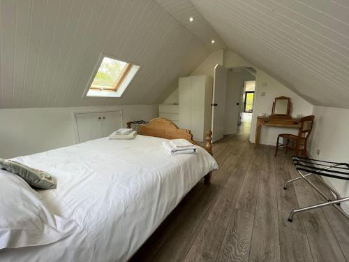 a bedroom with a large white bed in a attic at The Stable, Grove End Farm in Petworth