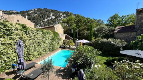 - une piscine dans une cour avec des parasols dans l'établissement Le 52 en Provence - Chambres ou Suite en B&B dans Authentique Mas de Village avec Piscine au pied du Luberon, à Robion
