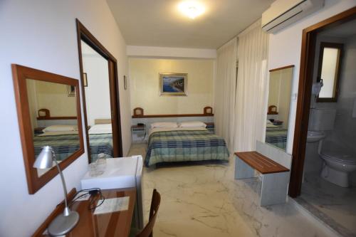 a hotel room with two beds and a mirror at Hotel Condor in Taormina