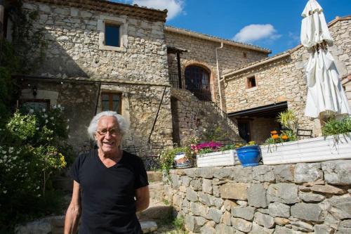 an older man standing in front of a stone house at Gîtes du Mas Champion - Piscine, Soleil, Nature & Calme - groupes in Saint-Just-et-Vacquières