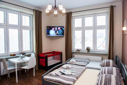 a hotel room with two beds and a table and windows at Cracow Apartaments in Krakow
