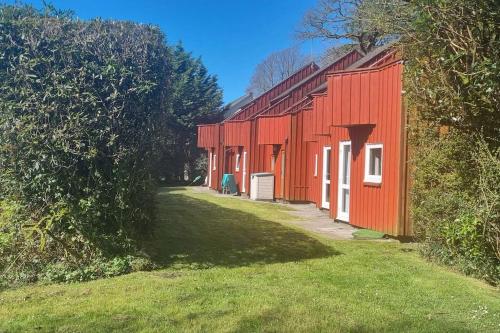 a red building with a green yard next to it at Woodland Lodge, Llanteglos Estate in Narberth