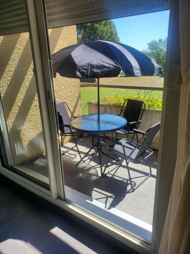 une table et des chaises avec un parasol sur une terrasse dans l'établissement Appartement piscine golf, à Saint-Cyprien
