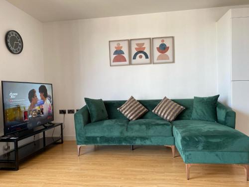 a living room with a green couch and a tv at Camden Town Apartment in London