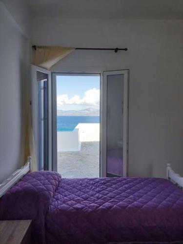 a bedroom with a purple bed with a view of the ocean at Beachfront Villa Gia Paros in Kampos Paros