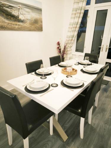 a white table with black chairs and a white dining room at Large 3 Bedroom Home, Sleeps 7, Ideal for Families & Contractors, Long-Stay Friendly, Hosted by Clark Property Estates in Southend-on-Sea