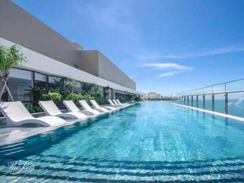 a swimming pool with white lounge chairs on a building at Chou'ka Homecation The Sóng in Vung Tau
