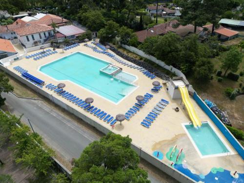 une vue aérienne d'une grande piscine avec des chaises et un toboggan dans l'établissement Charmant Mobil Home Camping Siblu, à Capbreton