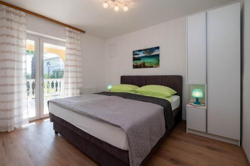 a bedroom with a large bed with green pillows at Apartments Šerbečić in Malinska