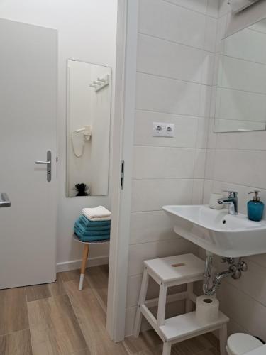 een witte badkamer met een wastafel en een spiegel bij Gábriel Apartman 2 in Kőszeg