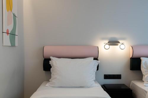 a bed with a white pillow and a lamp at PAREA Athens in Athens