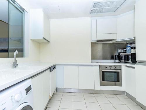 a white kitchen with white cabinets and a dishwasher at Fashion avenue Dubai Mall -The Residence in Dubai