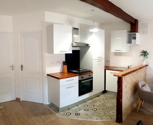 une cuisine avec des armoires blanches et une cuisinière dans l'établissement Vacances en famille 4 étoiles à 30min des pistes de Ski Mont Dore Sancy, à Messeix