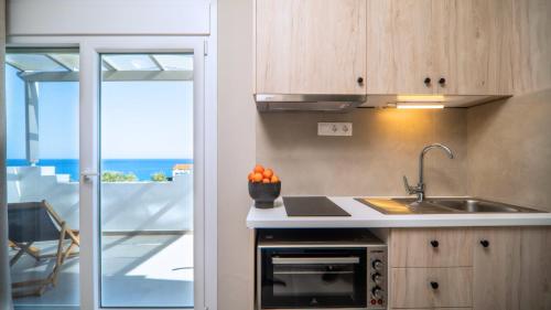 cocina con fregadero y vistas al océano en Fata Morgana Studios & Apartments, en Frangokastello