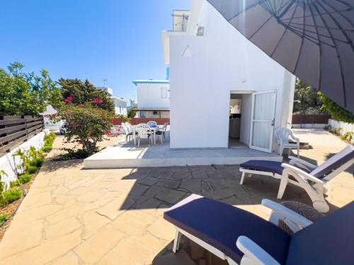 a patio with chairs and an umbrella next to a building at Protaras Sunny Villa in Protaras