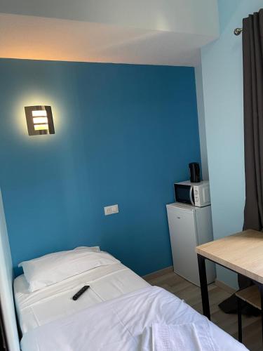 盧爾德的住宿－Résidences saint pierre，一间卧室设有蓝色的墙壁、一张床和一张桌子