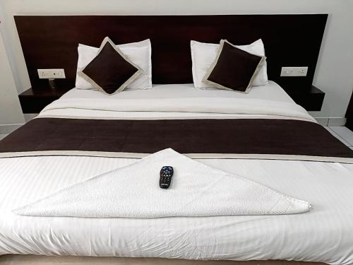 a remote control sitting on top of a white bed at Grace Tourist Home in Ernakulam